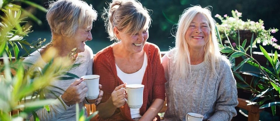 Three friends sitting outdoors together with cups of tea
